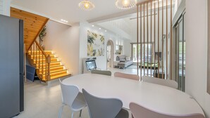 A modern interior with a large dining table, a staircase with wooden steps, and a view of a pool area. - Gapyeong Jinikidsdogchaepoolvilla (Gapyeong)