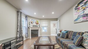 Una sala de estar con un sofá, una mesa de centro de vidrio, una chimenea y un cuadro en la pared.