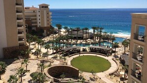 A resort with a pool area, palm trees, and a view of the ocean. - Luxury oceanfront resort suite with access to Greg Norman Signature golf course! (Cabo San Lucas)