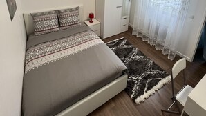 Une chambre à coucher comprenant un lit, une table de chevet, une lampe, une armoire et une chaise.