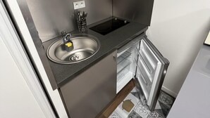 Une cuisine compacte dotée d’un évier encastré, d’un petit plan de travail et d’un réfrigérateur.