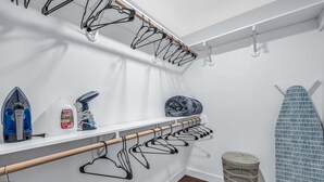 Un espace dédié à la lessive, équipé d’un étendoir, d’une planche à repasser et d’étagères de rangement.