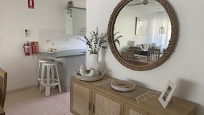 Une cuisine moderne avec des meubles blancs, une table à manger en bois et un grand miroir.