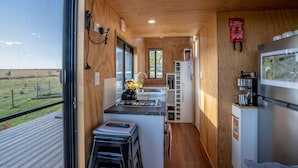 A compact kitchen with wooden walls, a small island, and a refrigerator. - Eco tiny home williwa (Portland)
