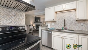 A modern kitchen with a black stove, white cabinets, and a herringbone-patterned backsplash.