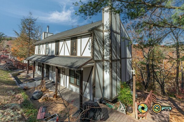 A modern house with a large deck, a chimney, and a view of the surrounding trees. - Cozy Renovated Woodland Townhome | Minutes from Bryce Resort! (Basye)