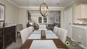 A dining room with a wooden table, beige upholstered chairs, and a chandelier.