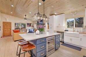 Una cucina moderna con isola centrale, mobili bianchi e ventilatore a soffitto.