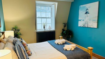 Une chambre à coucher avec un lit, une fenêtre, un radiateur, une lampe et un tableau accroché au mur.