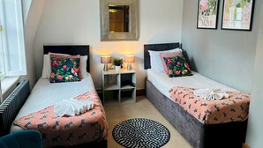 A bedroom with two beds, a bedside table, a mirror, and a window. - Pebble Mews House - Sleeps 6 to 8 Guests (Brighton)