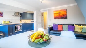 A modern kitchen with a dining area, a sofa, and a painting on the wall.