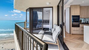 En balkon med havudsigt, et moderne køkken med træskabe, og et soveværelse med et stort vindue.