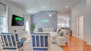 Un salon moderne avec un mur orné d’un motif, un téléviseur à écran plat et un canapé.