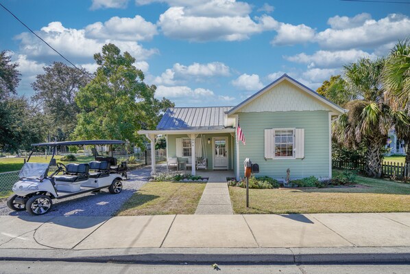 A light green house with a porch, a mailbox, and a golf cart parked in front. - On Main St! Private Heated pool, Golf cart included, Sleeps 10 (Bay St. Louis)
