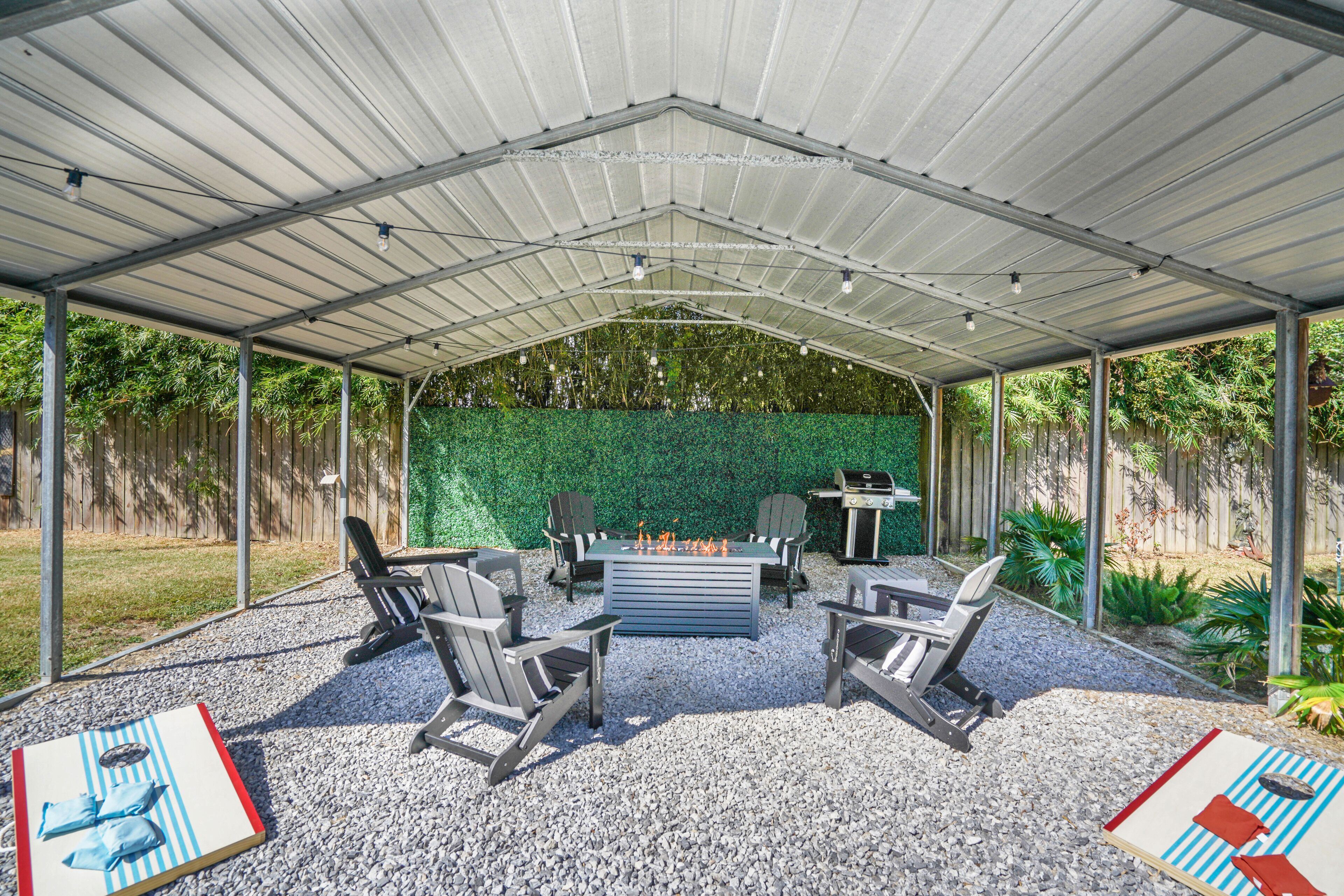Een overdekt terras buiten met een vuurkorf, zitgedeelte en een groene wand.