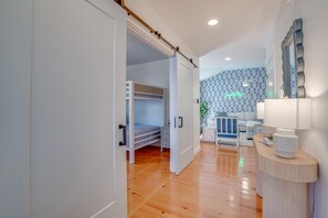 A modern bedroom with a bunk bed, a white wardrobe, and a bedside table with a lamp. - On Main St! Private Heated pool, Golf cart included, Sleeps 10 (Bay St. Louis)