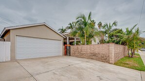 A residential garage with a white door, a brick wall, and a concrete driveway. - Cozy, spacious 4B4B house with high-speed internet near Disney (West Covina)
