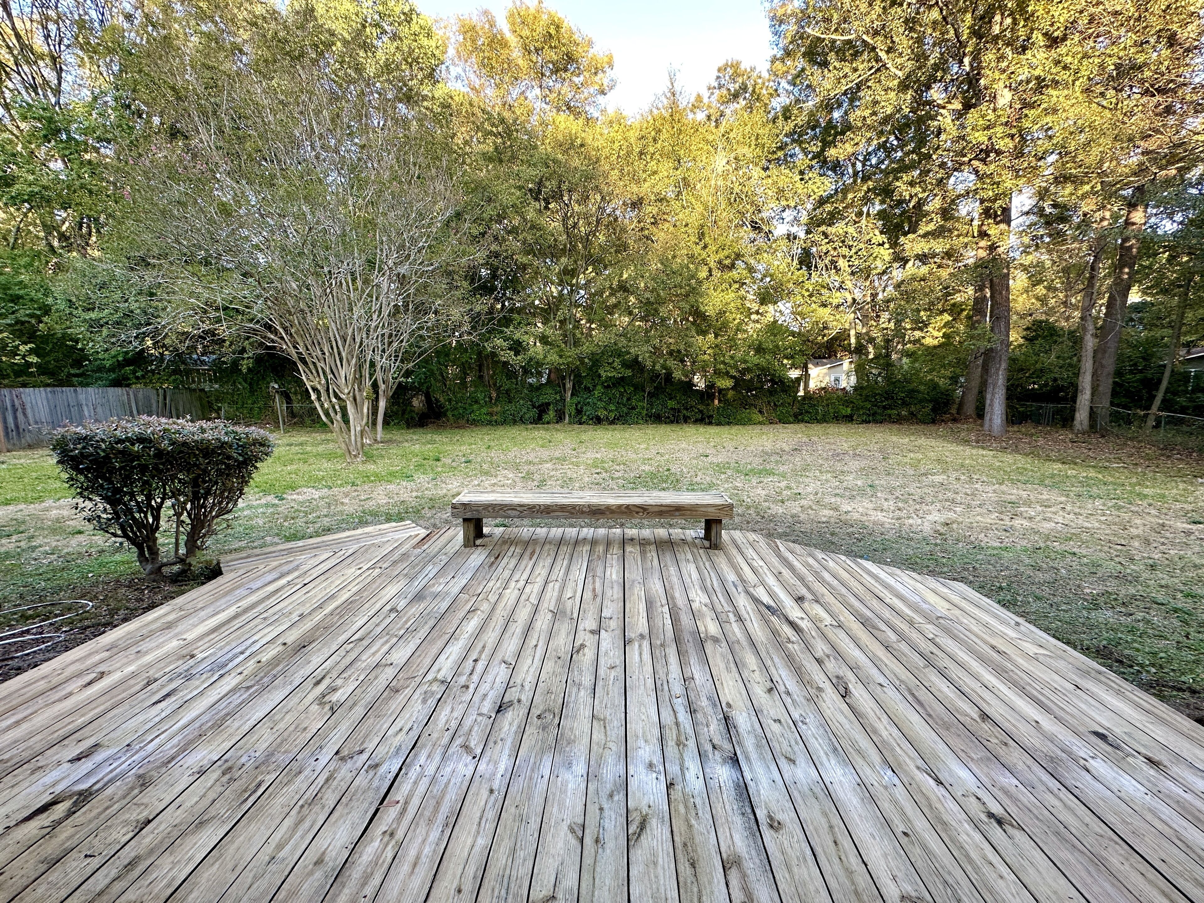 Une terrasse en bois avec un banc, située dans un jardin.