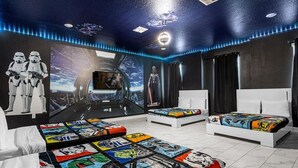 Ein Schlafzimmer mit Star Wars-Dekor, darunter eine Wandmalerei, Bettwäsche mit Comicfiguren und ein Bett mit Star Wars-Kopfschild.