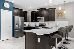 Enjoy cooking in this well-equipped kitchen with a central island, bar stools, and stainless steel appliances.