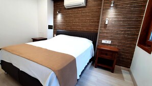 Een hotelkamer met een bed, nachtkastjes, een houten wandpaneel, een airconditioning en een raam.