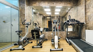 Een sportschool met diverse fitnessapparatuur, waaronder loopbanden, hometrainers en een roeimachine.