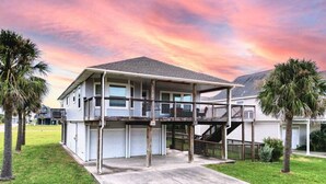 A two-story house with a covered porch, a garage, and a driveway. - Bounty Pet Friendly · Entertain & Relax at our Beach Home - Pet Friendly (Galveston)