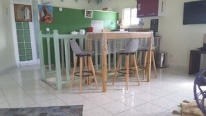 A dining area with a green wall, a white door, and a tiled floor. - Le Gosier Spacious loft with small sea view (Le Gosier)
