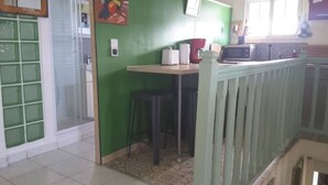 A room with a green wall, a white-framed window, a small table with a red chair, and a white radiator. - Le Gosier Spacious loft with small sea view (Le Gosier)