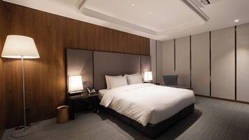 Una habitación de hotel moderna con una cama grande, dos lámparas de noche, un teléfono y un cesto de basura.