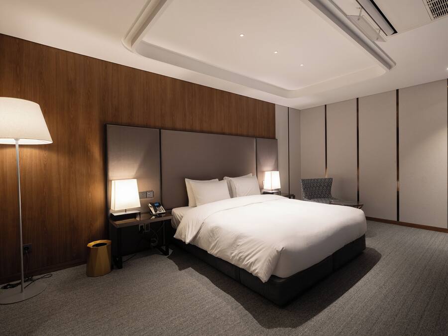 Una habitación de hotel moderna con una cama grande, dos lámparas de noche, un teléfono y un cesto de basura.