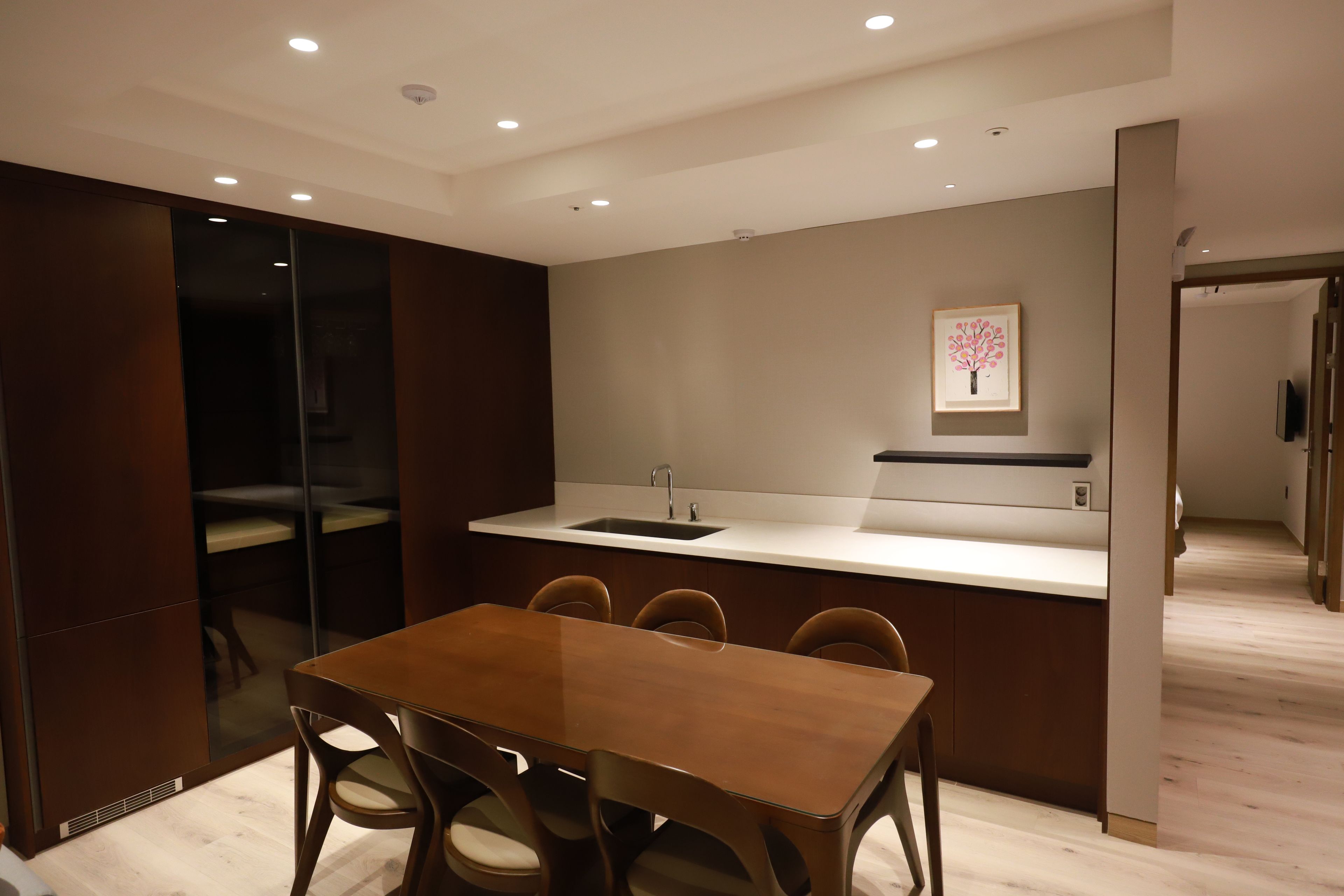 Une cuisine moderne avec un coin repas, comprenant une table et des chaises en bois, un four encastré et un évier.