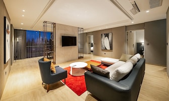 Una sala de estar moderna con un sofá, sillones, una mesa de centro y un televisor.