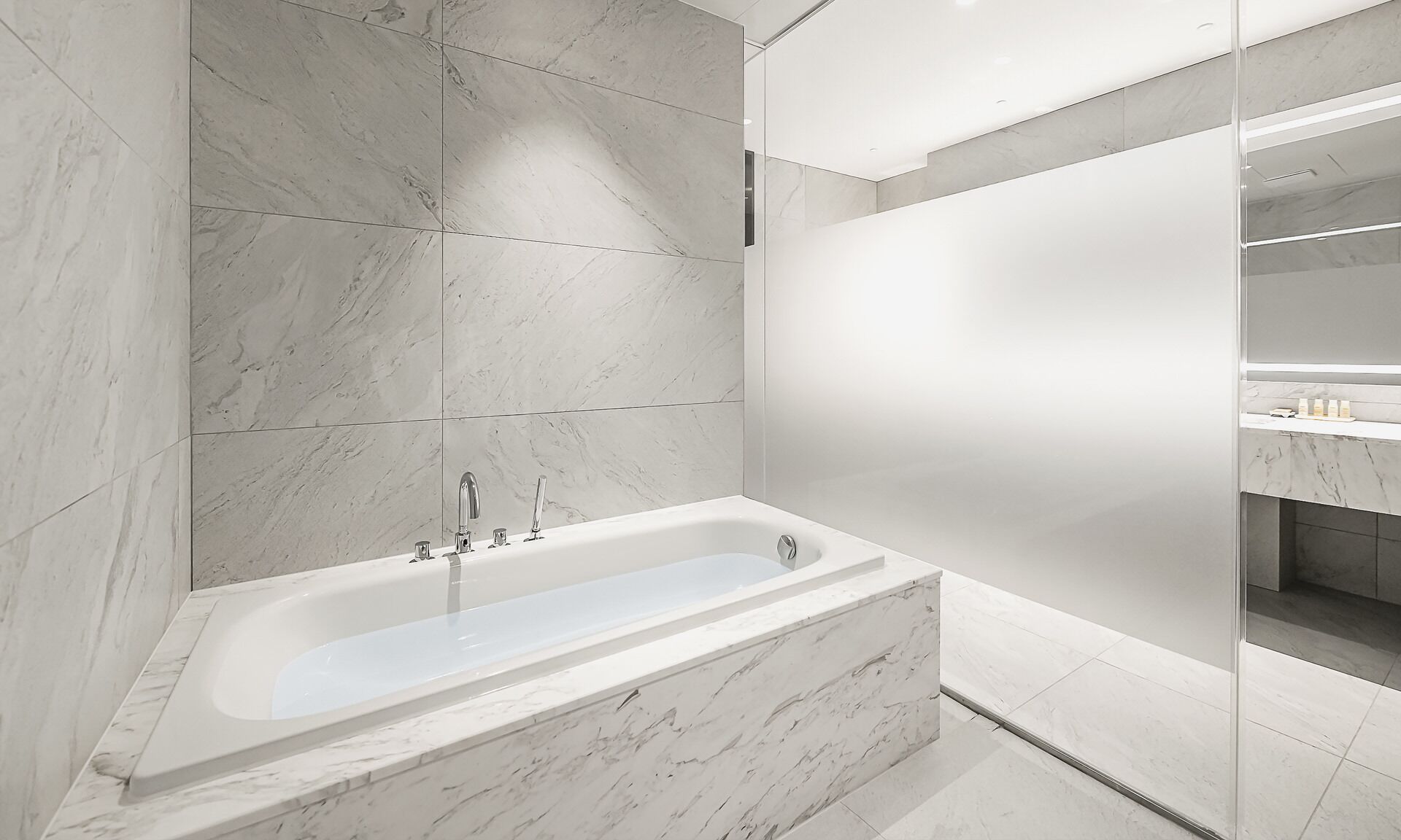 Een moderne badkamer met een vrijstaand bad, marmeren tegels en een minimalistisch design.