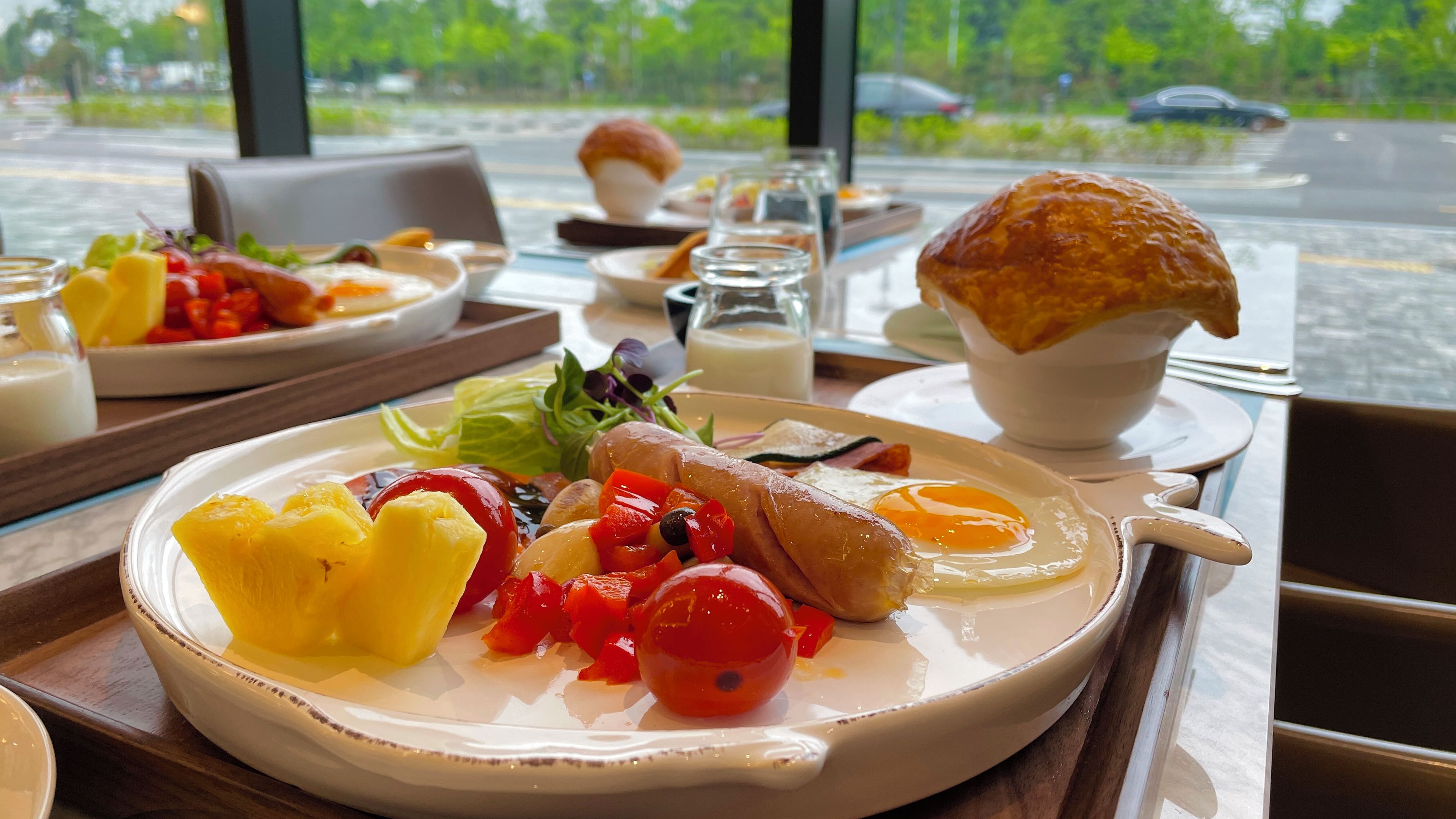 A breakfast setting with a plate of eggs, vegetables, and a croissant.