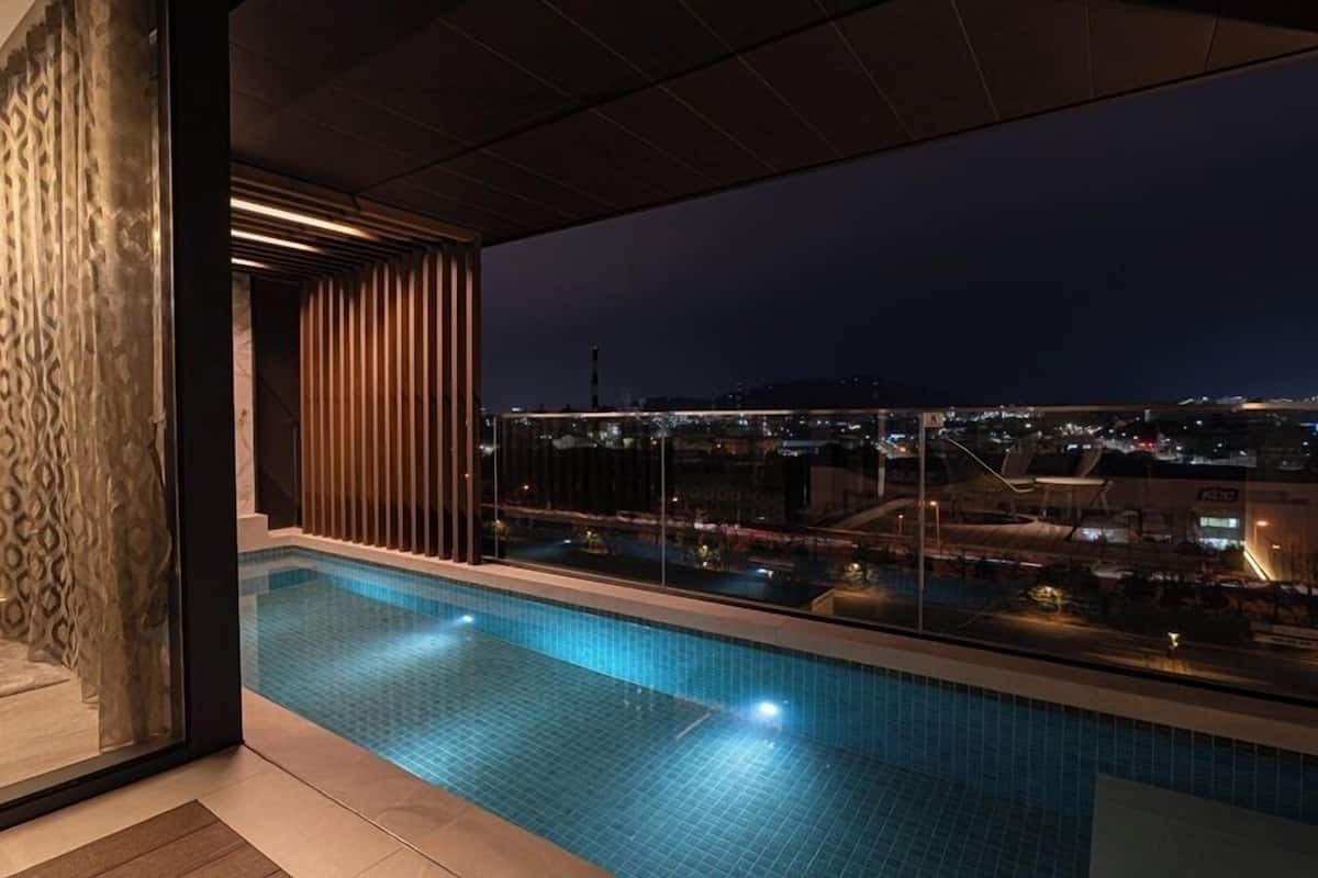 A modern indoor swimming pool with a city view at night.
