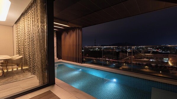 Piscina interior moderna con vista a la ciudad de noche.