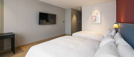 Una habitación de hotel moderna con una cama grande, un televisor montado en la pared y una mesita de noche con lámpara.