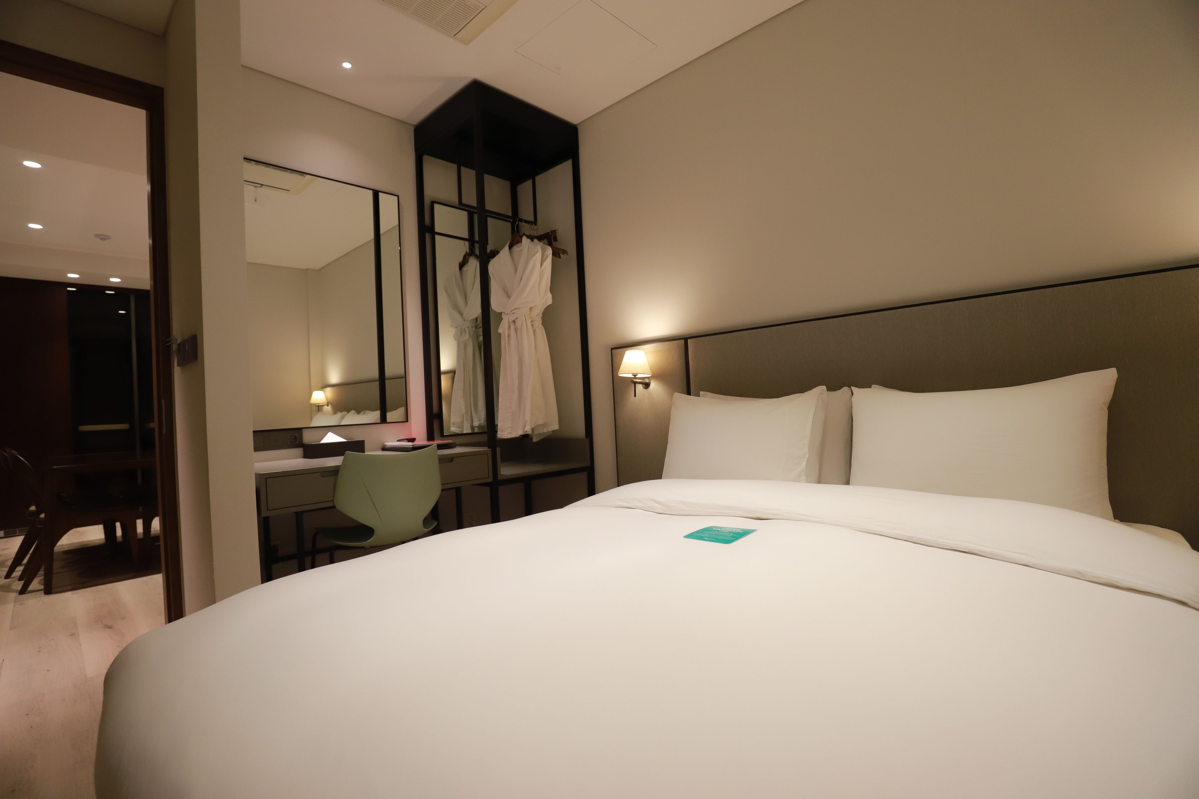 Una habitación de hotel con una cama grande, un escritorio, una silla y un espejo.