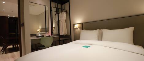 Una habitación de hotel con una cama grande, un escritorio, una silla y un espejo.