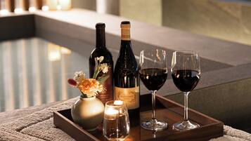 A tray with wine bottles and glasses on a table in a room with a view.