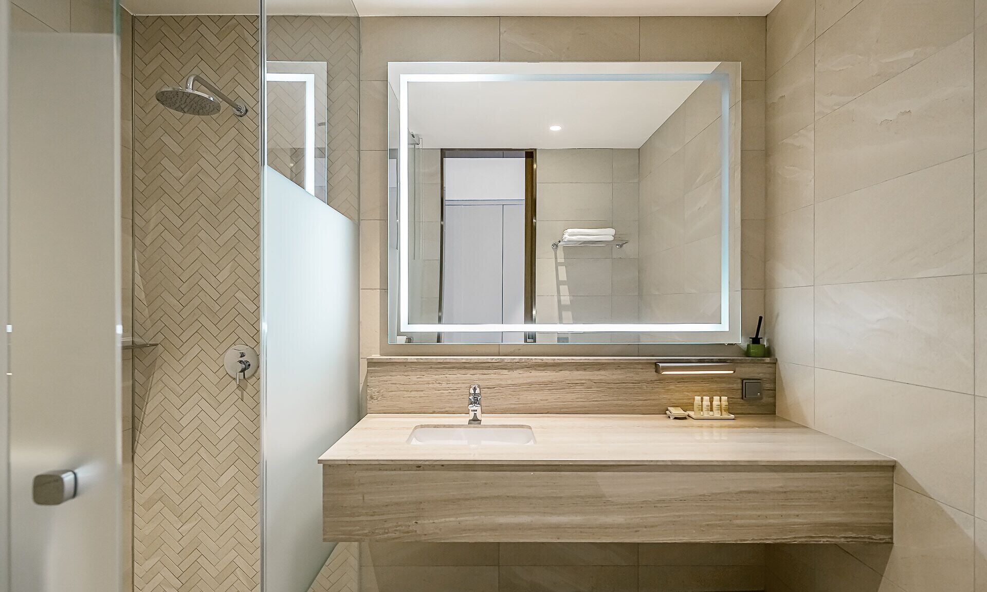 A modern bathroom with a large mirror, a sink, and a shower.
