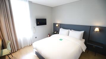 A hotel room with a large bed, two bedside lamps, a flat-screen TV, and a chair.