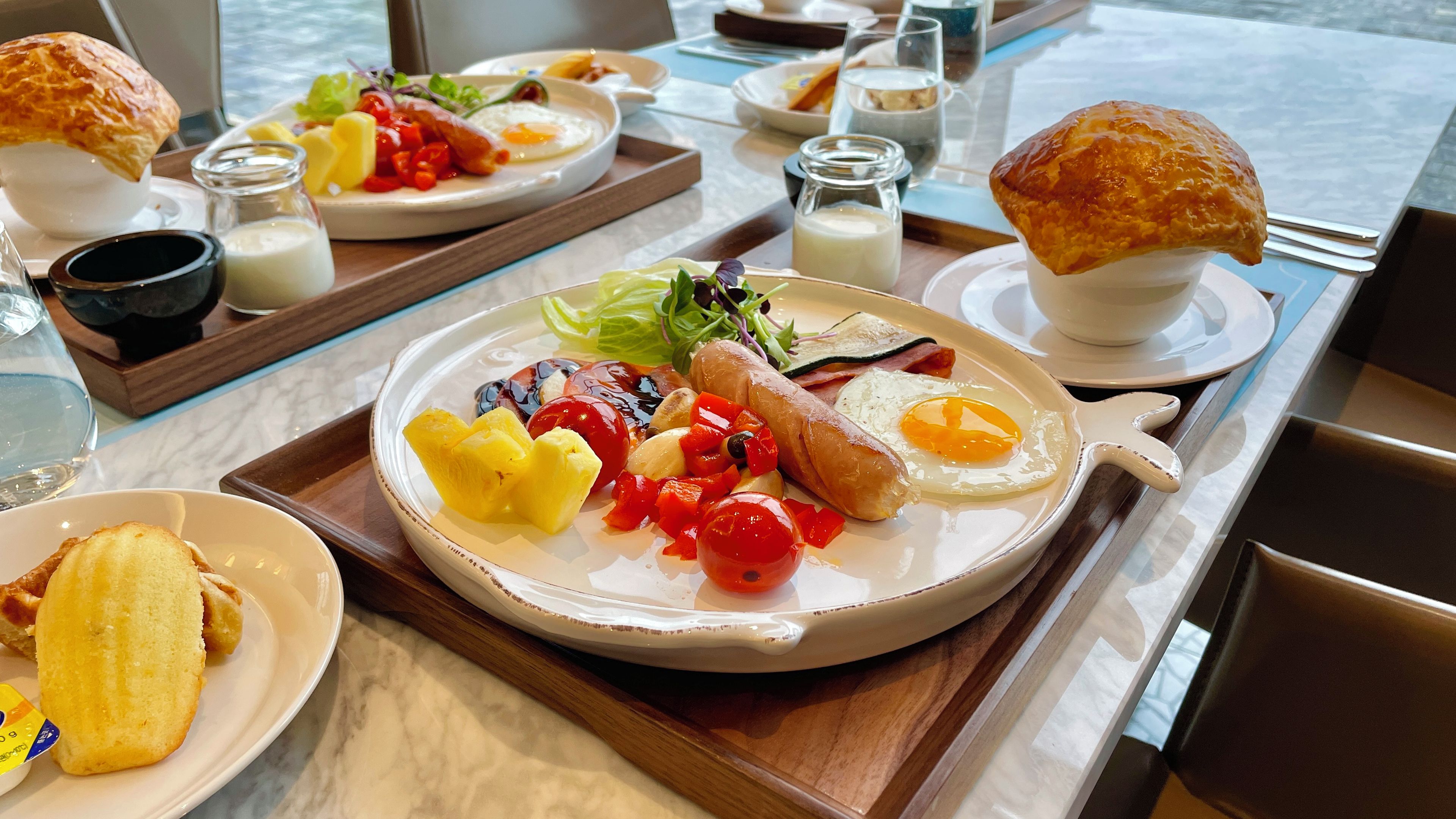Un bufé de desayuno con diversos platos, incluyendo huevos, salchichas y frutas.
