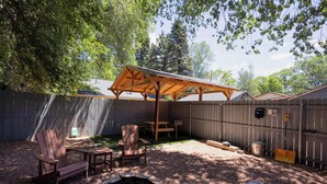 Takapihalla on puinen pergola, kaksi Adirondack-tuolia, nuotiopaikka ja piknikpöytä.