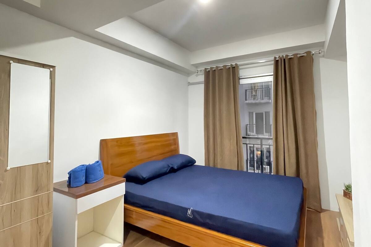 Ein Schlafzimmer mit einem Holzbett, einem kleinen Schreibtisch und einem Fenster mit Vorhängen.