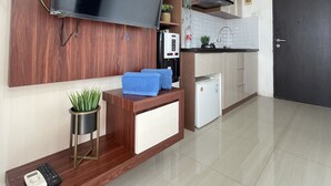 Eine moderne Küche mit integriertem Fernseher, Holzschränken, einer Kaffeemaschine und einem kleinen Kühlschrank.