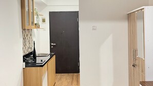 Eine kleine Küche mit Holzausstattung, einer schwarzen Tür und einer weißen Wand.