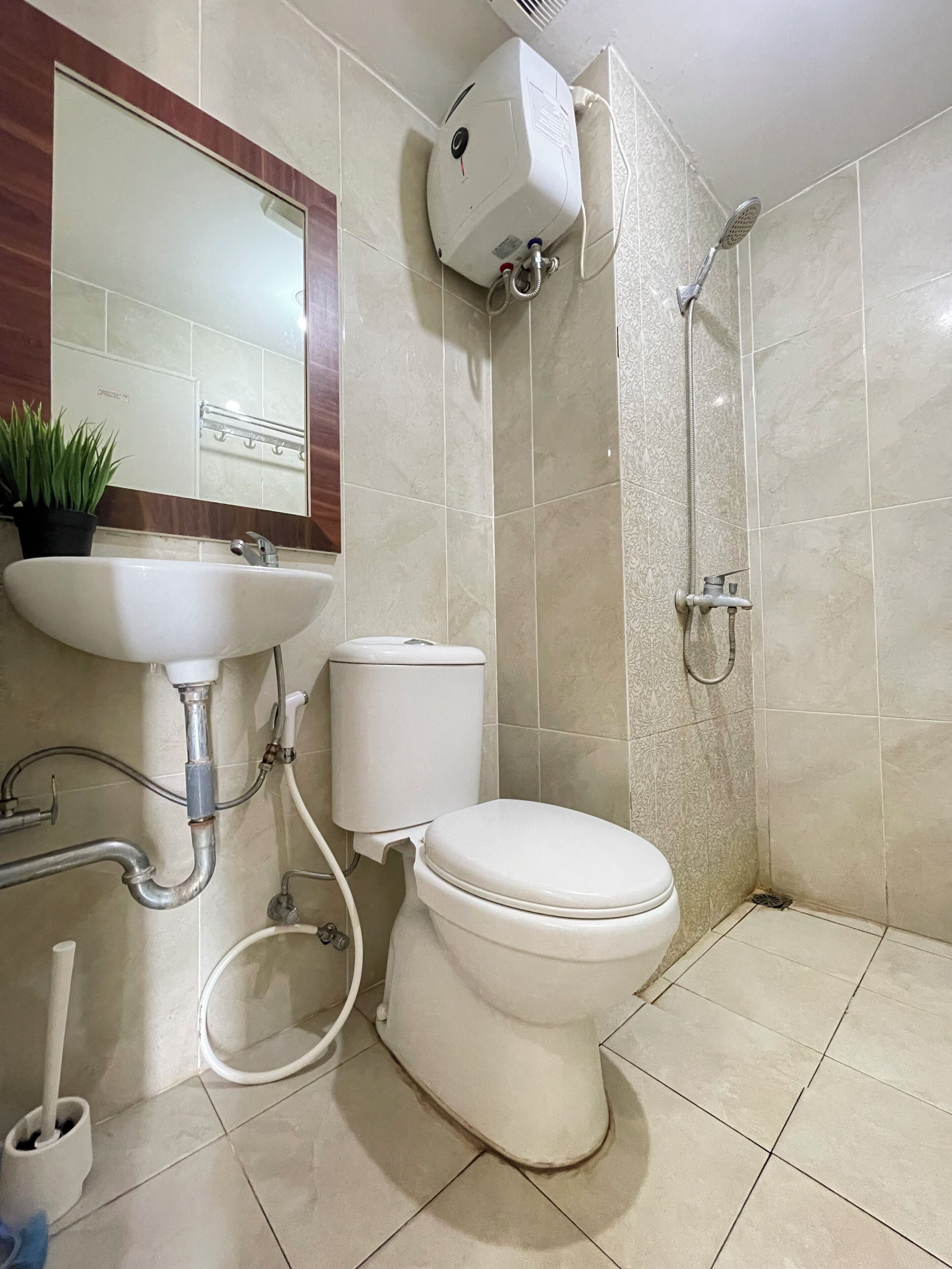A bathroom with a toilet, sink, shower, and a mirror.