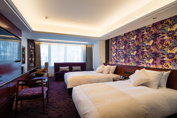 Habitación de hotel con dos camas, un escritorio, una silla y un amplio diseño floral en la pared.